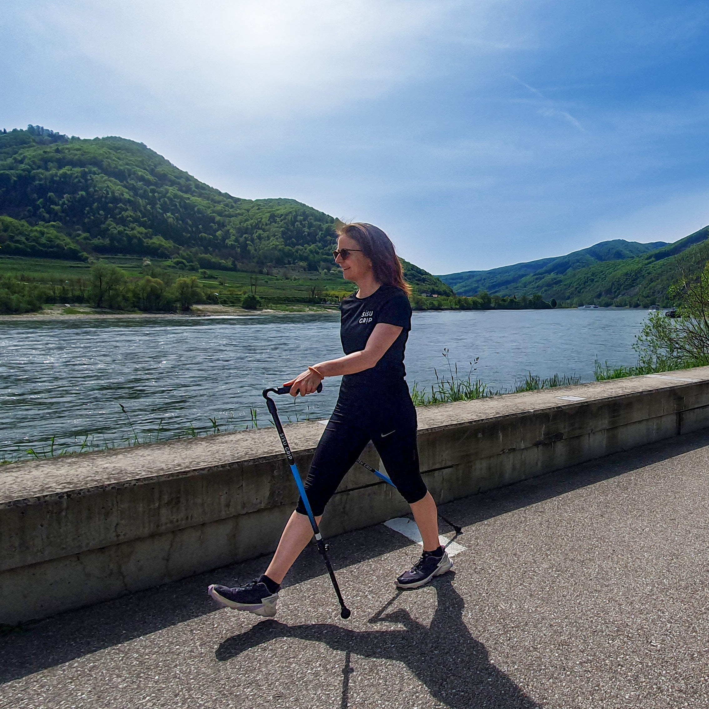 Kävelijä käyttää Sisu Grip sauvoja järven rannalla