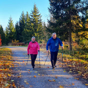 Kaksi kävelijää käyttää Sisu Grip sauvoja metsäpolulla